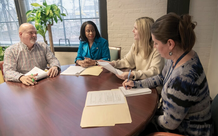 TABLE TALK: Anika Kimble-Huntley, second from left, chief marketing officer at R.I. Commerce Corp., confers with her staff at the R.I. Commerce headquarters in Providence. The staff includes, from left, Mark Brodeur, director of international and domestic group sales; Lindsay Russell, deputy director of communications and stakeholder engagement; and Robin Erickson, domestic tourism and marketing operations director. PBN PHOTO/MICHAEL SALERNO