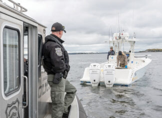 NAVIGATING SHORTAGES:  R.I. environmental police officer Jacob Malone, left, checks the size of striped bass caught by two unidentified fishermen in Narragansett Bay. The R.I. Department of Environmental Management says staff shortages have made it difficult to schedule such law enforcement ­operations.  PBN PHOTO/ DAVID HANSEN