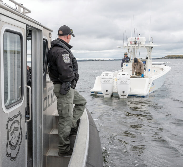 DISADVANTAGES OF NAVY.  RI Environmental Police Officer Jacob Malone, left, checks the size of a striped bass caught by two unidentified anglers in Narragansett Bay.  The RI Department of Environmental Management says staffing shortages have made it difficult to schedule such enforcement actions.  PBN PHOTO/ DAVID HANSEN